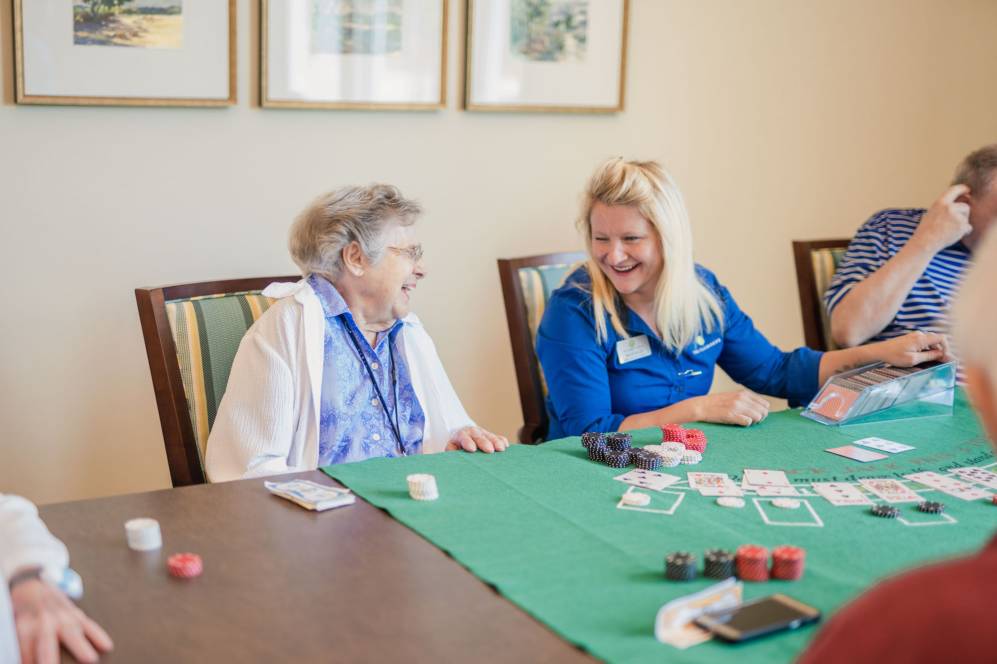The Claiborne at Baton Rouge senior resident and employee playing cards in the game room
