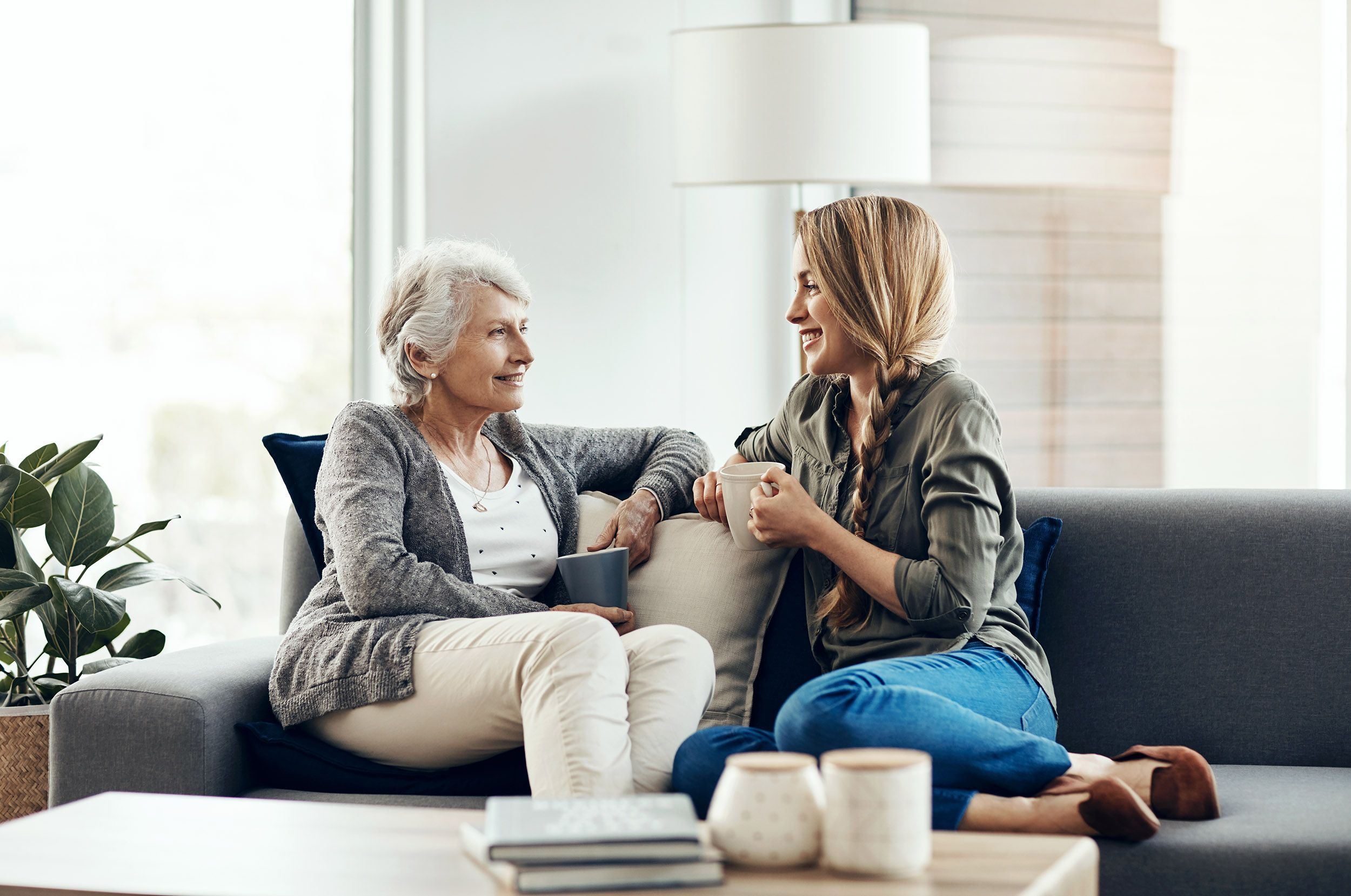 Adult woman talking and smiling with elderly mother on couch
