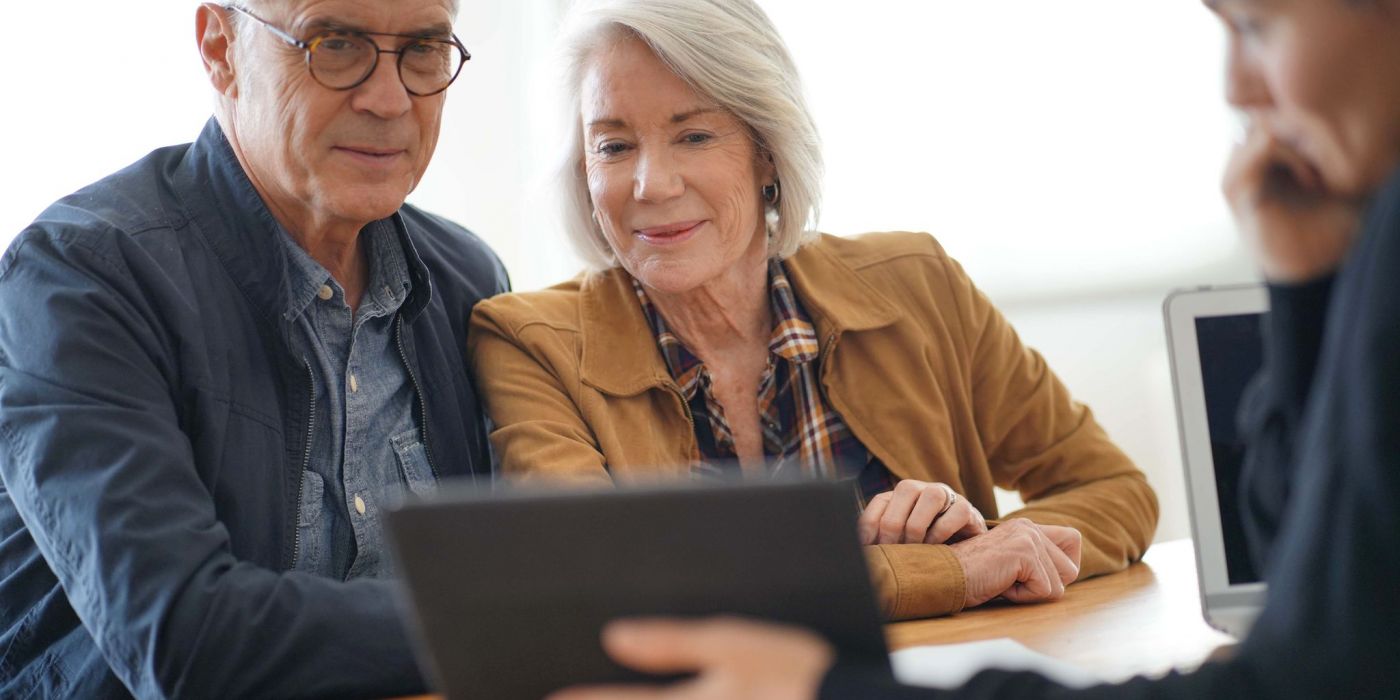 Modern senior couple looking at a tablet with an advisor.