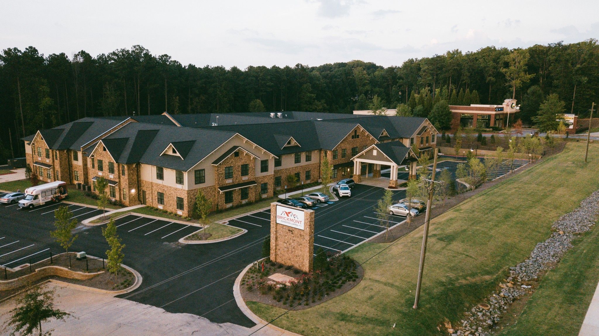 Brickmont at Acworth senior living community aerial view of assisted living community exterior and parking lot surrounded by forest