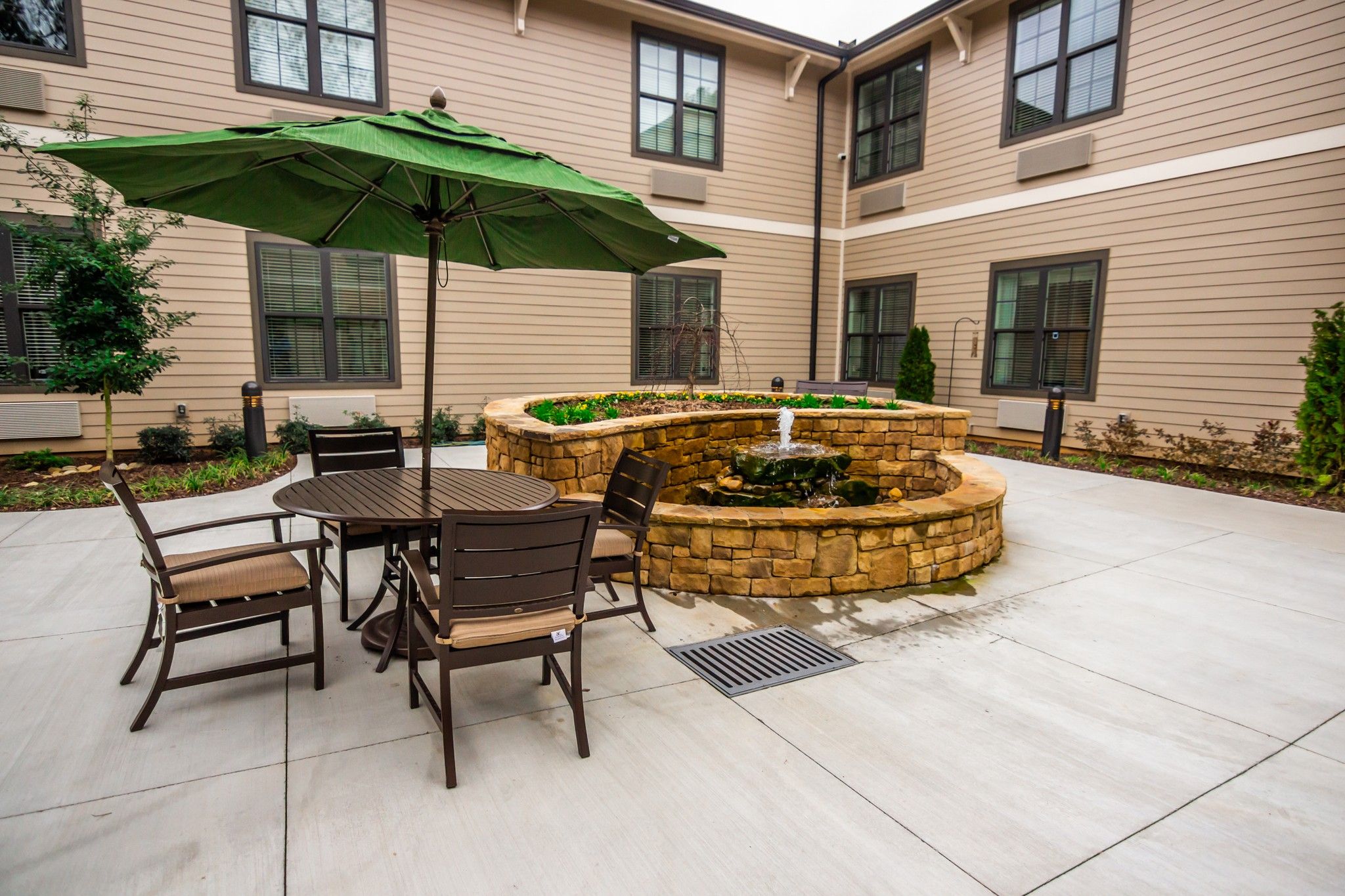 Brickmont at Acworth outdoor patio courtyard with gardens, tables, chairs, and umbrellas