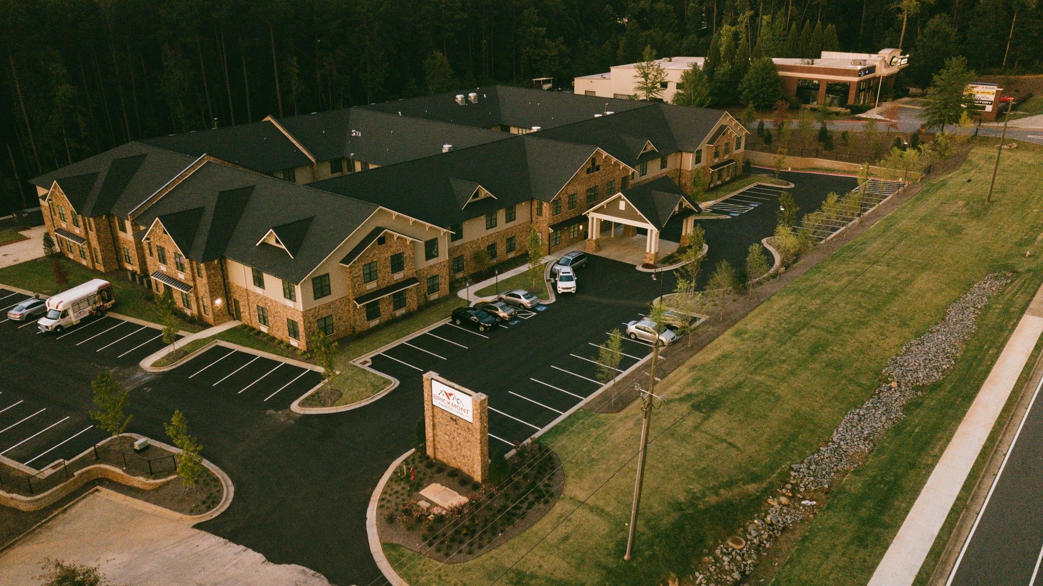 Brickmont at Acworth senior living community aerial view of assisted living community exterior and parking lot surrounded by forest