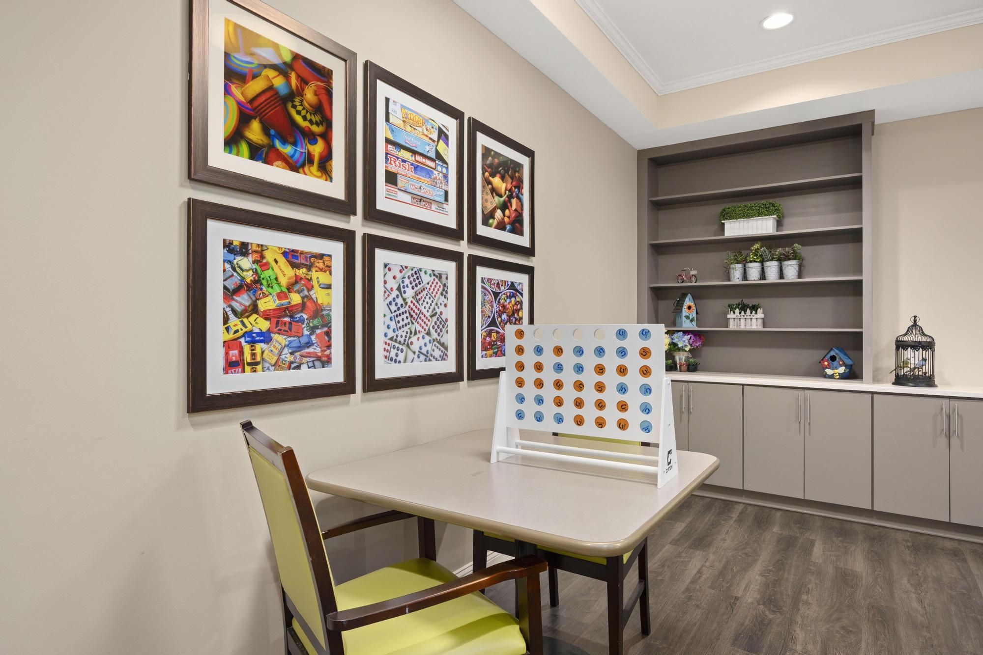 Brickmont at Acworth resident gaming lounge amenity with tables, chairs, games, and wall art