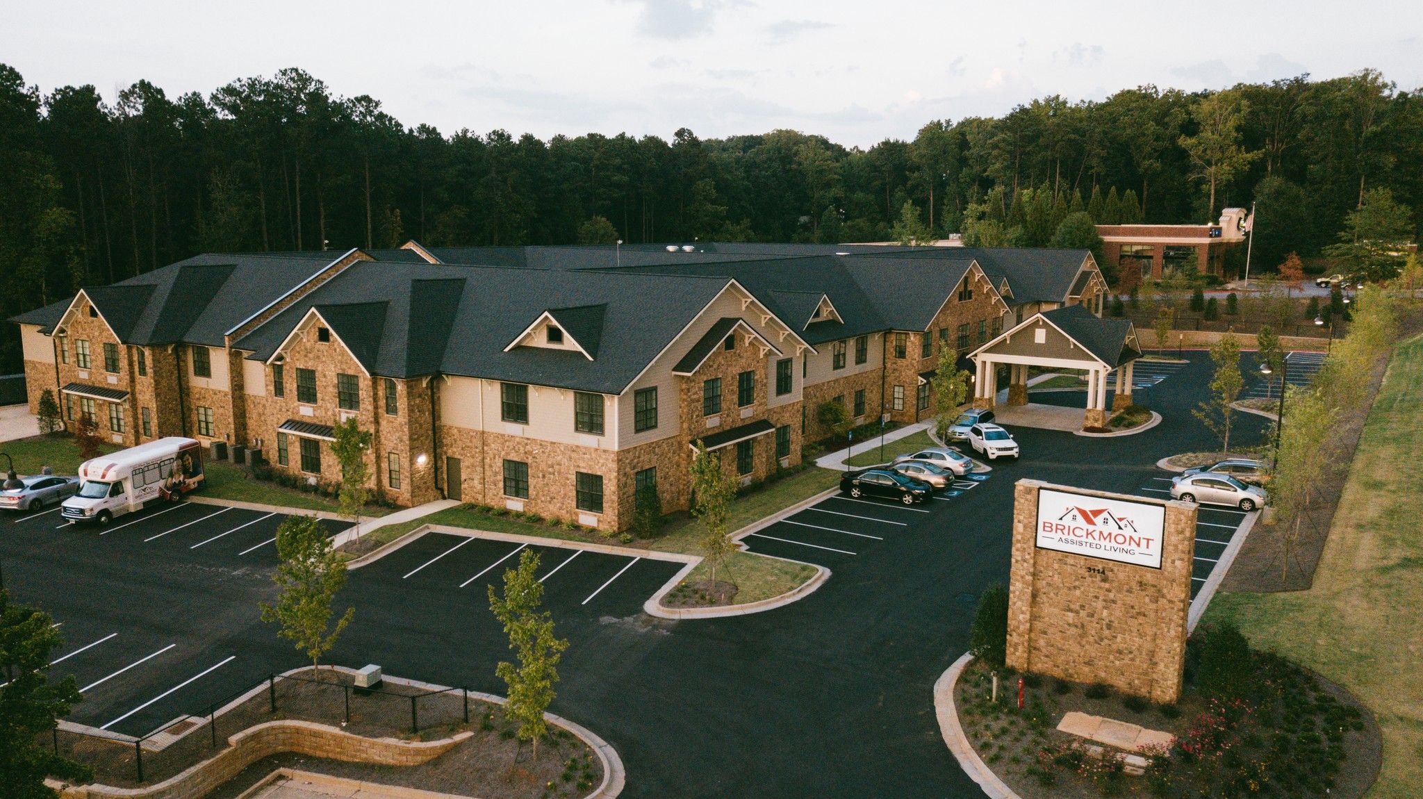 Brickmont at Acworth senior living community aerial view of assisted living community exterior and parking lot surrounded by forest