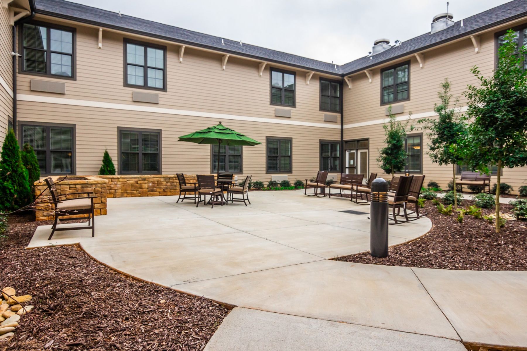 Brickmont at Johns Creek outdoor patio courtyard with gardens, tables, chairs, and umbrellas