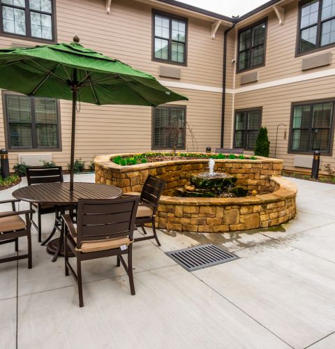 Brickmont at Johns Creek outdoor patio courtyard with gardens, tables, chairs, and umbrellas