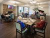 Brickmont at Johns Creek resident dining room amenity with tables and chairs, a stone fireplace, and grand piano