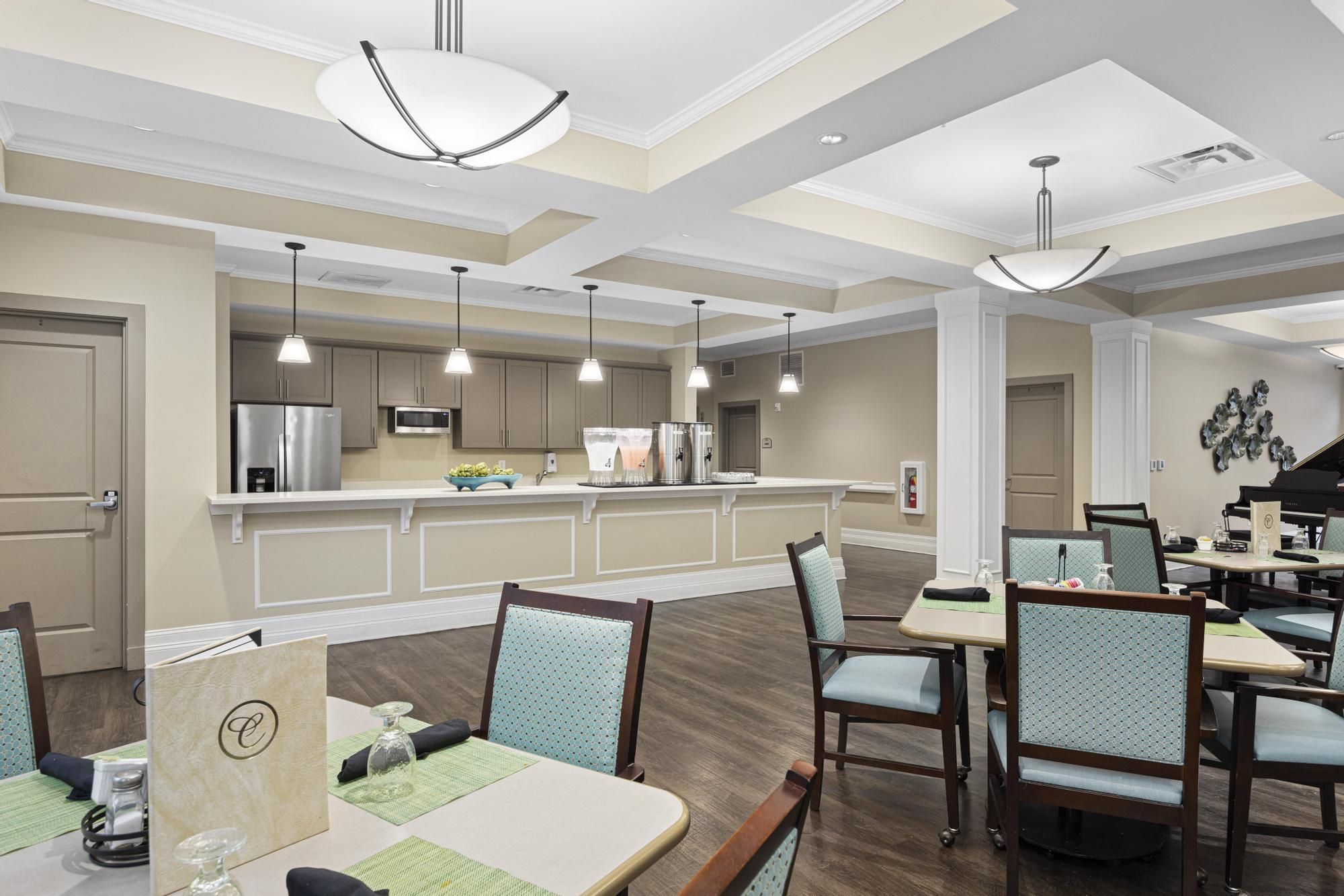 Brickmont at Johns Creek resident dining room amenity with tables and chairs, a stone fireplace, and grand piano