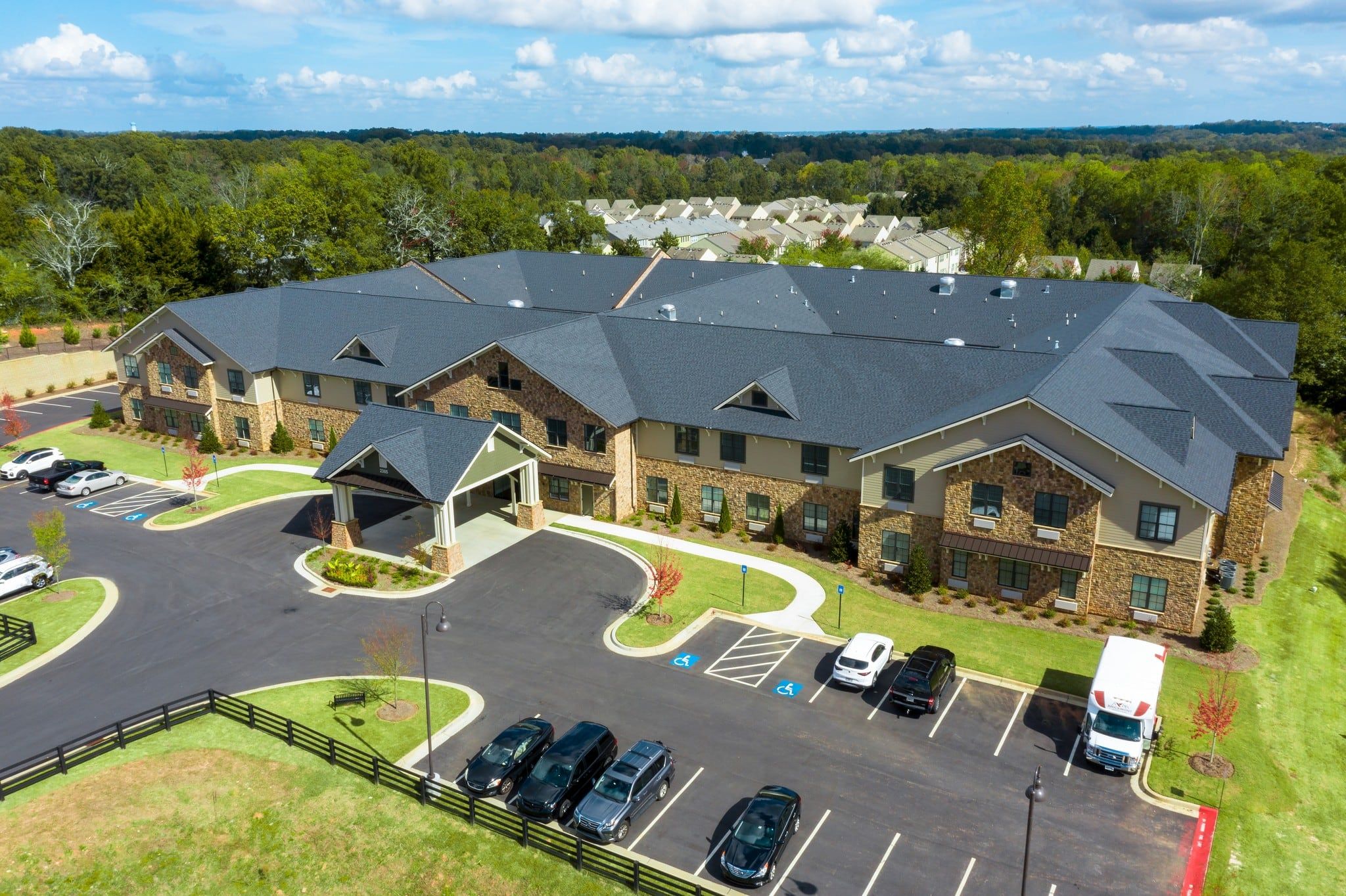 Brickmont at Johns Creek   senior living community aerial view of assisted living community exterior and parking lot surrounded by forest