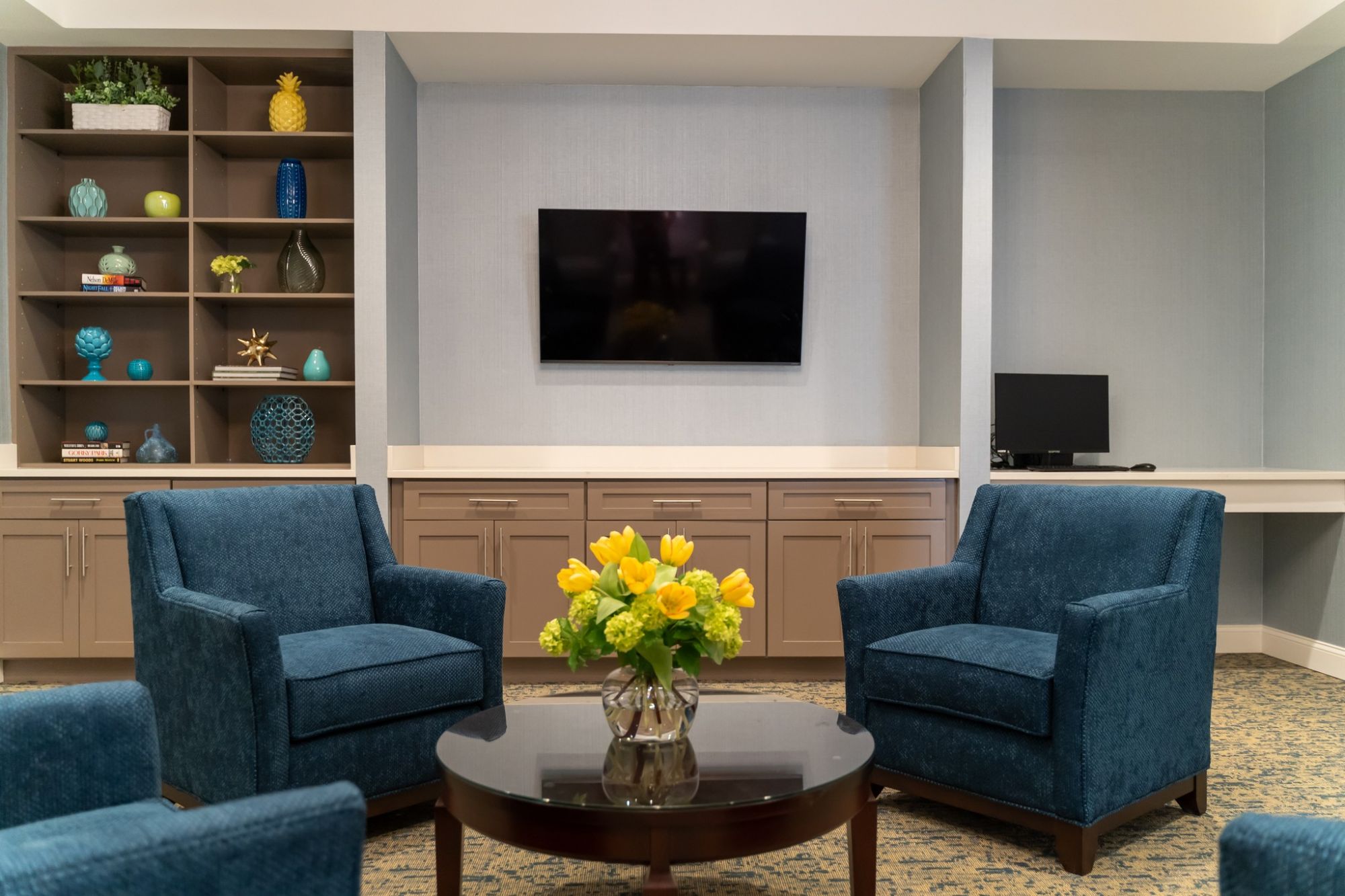 Brickmont at John's Creek senior living community common sitting area with lounge chairs, tvs, bookshelves, and a computer station