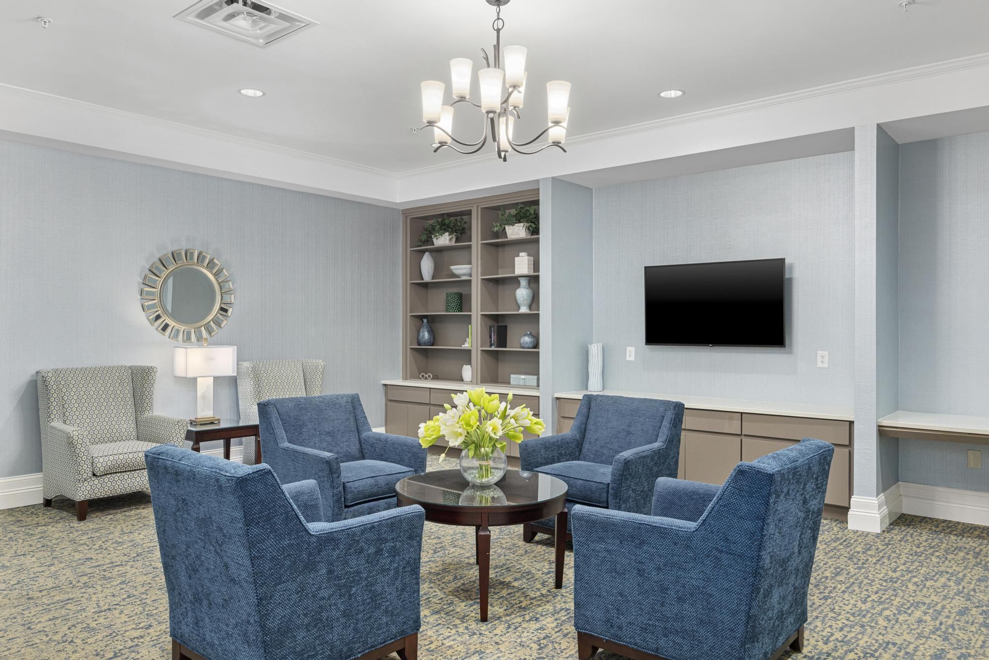 Brickmont at Johns Creek senior living community building elevator seating area with comfy chairs, table, lamp, and wall art