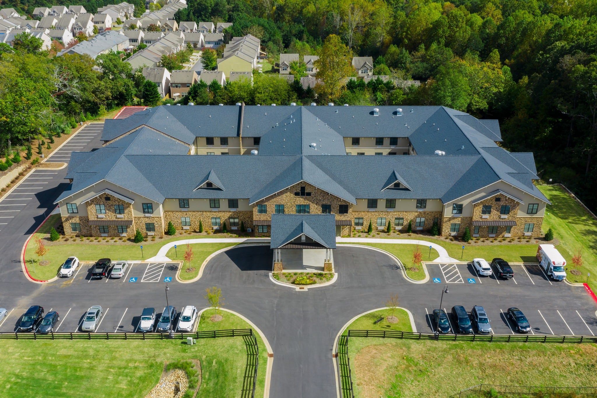 Brickmont at Johns Creek aerial view of assisted living community exterior and parking lot surrounded by forest