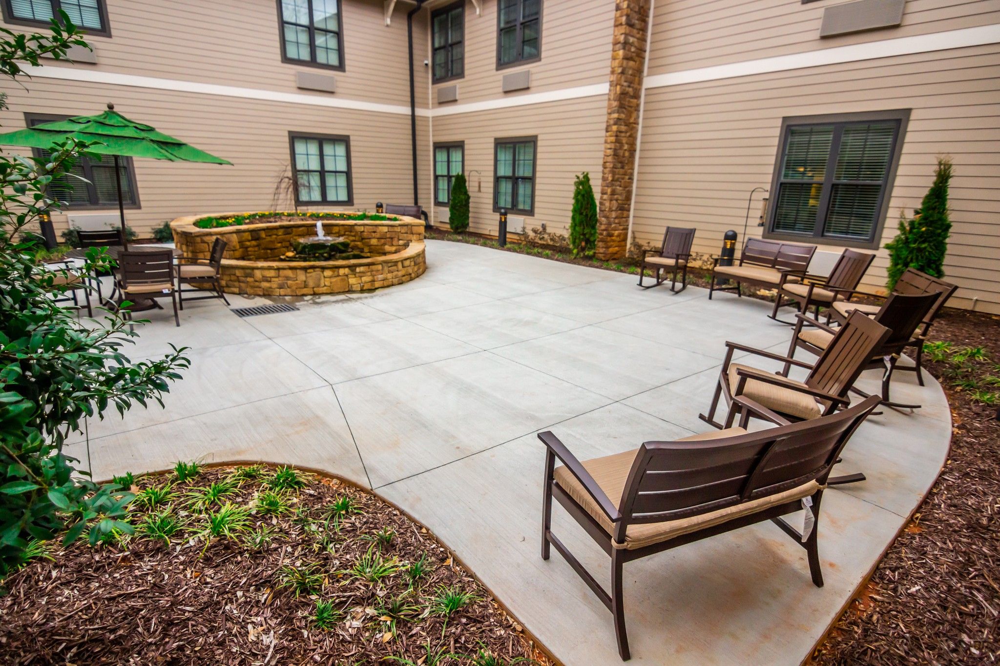 Brickmont at Johns Creek outdoor patio courtyard with gardens, tables, chairs, and umbrellas