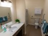 Brickmont at Johns Creek senior living community apartment bathroom with accessible sink, toilet, shower, and ample storage