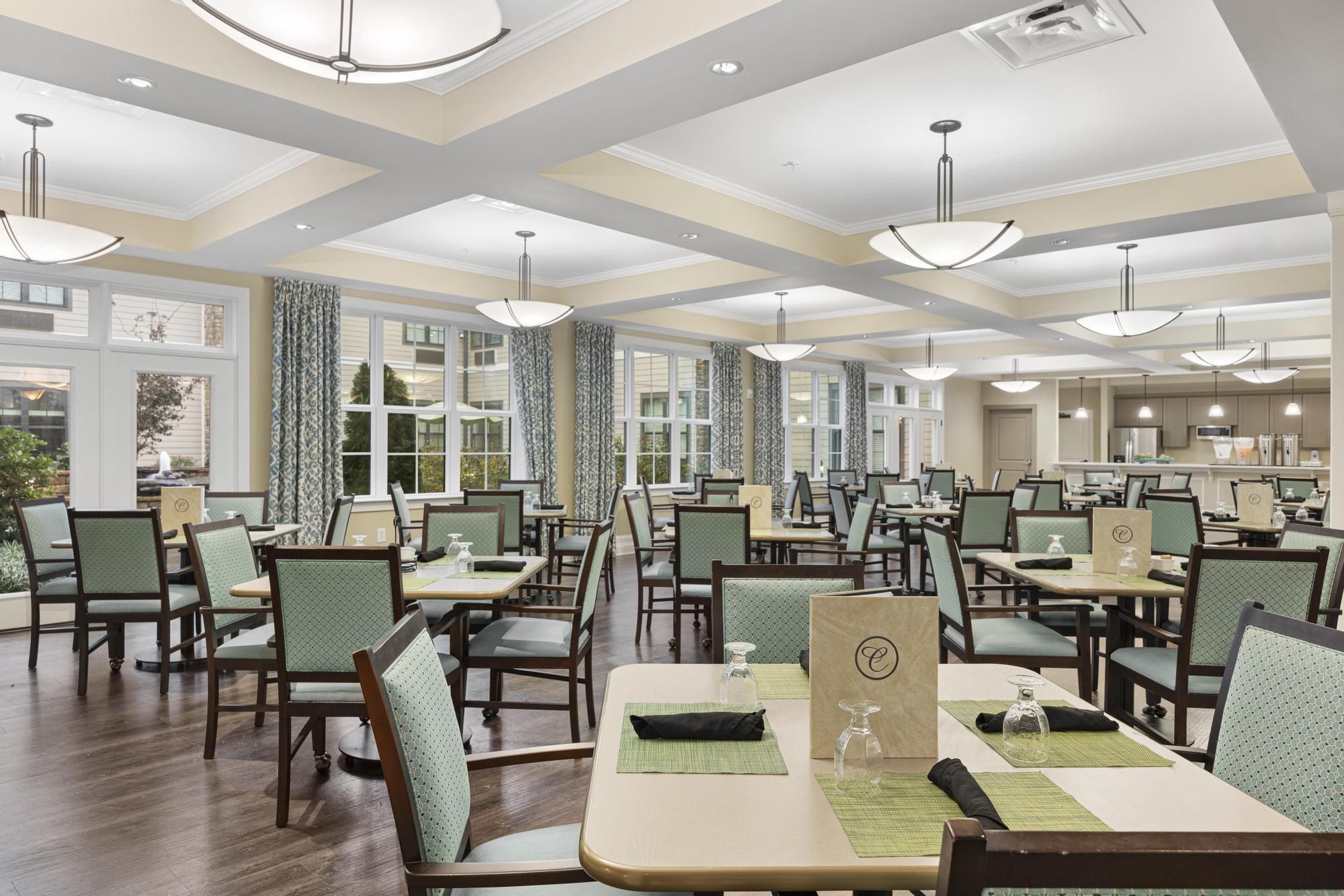 Brickmont at Johns Creek resident dining room amenity with tables and chairs, a stone fireplace, and grand piano