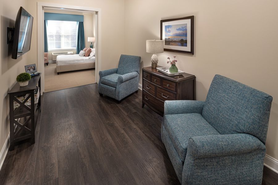 Brickmont at Roswell apartment living room with lounge chairs, cabinet, and mounted flat screen tv