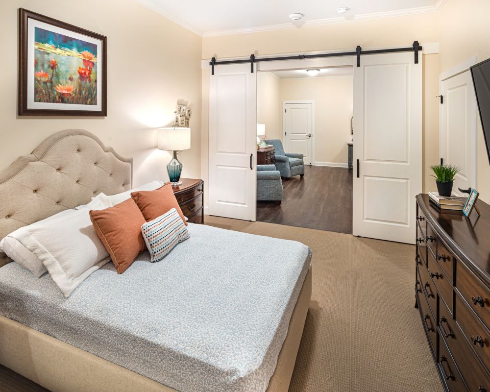 Brickmont at Roswell apartment bedroom with full sized bed, carpeting, and sliding barn doors to main living space