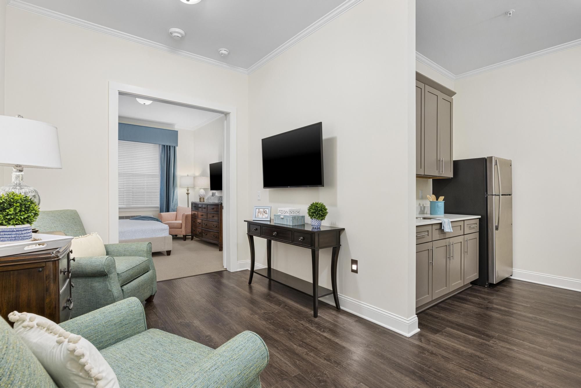 Brickmont at Roswell apartment living room with lounge chairs, cabinet, and mounted flat screen tv