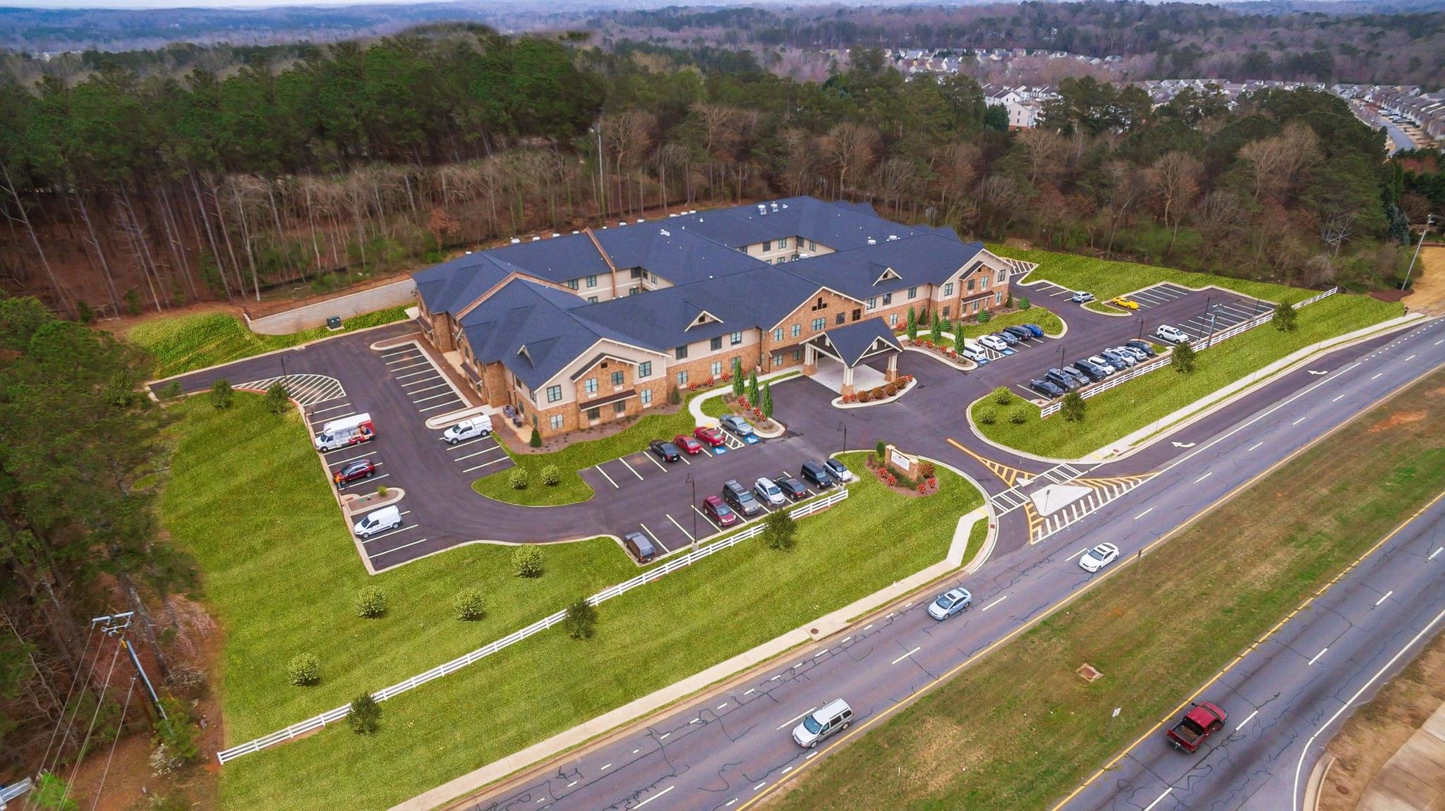 Brickmont at Roswell aerial view of assisted living community exterior and parking lot surrounded by forest