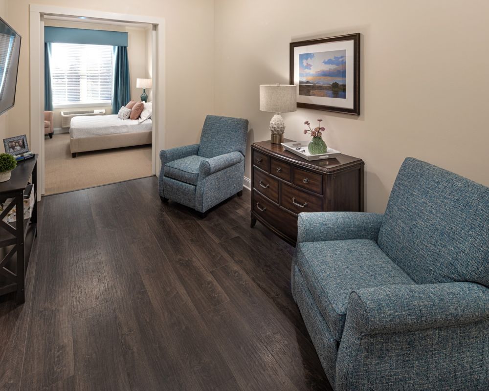 Brickmont at Roswell apartment living room with lounge chairs, cabinet, and mounted flat screen tv