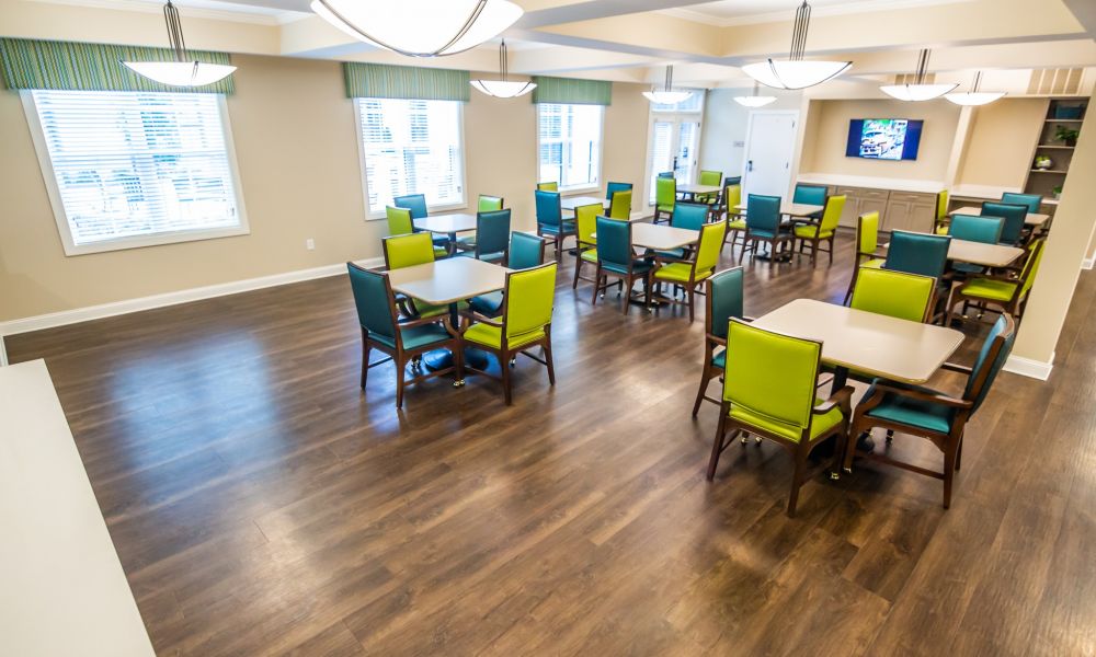 Brickmont at West Cobb resident activity lounge amenity with tables, chairs, large windows, and a flat screen tv