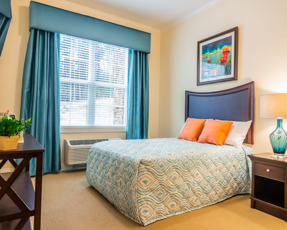 apartment bedroom with full sized bed, carpeting, and large windows