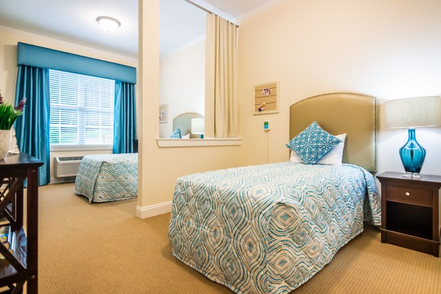 spacious shared apartment bedroom furnished with two beds, carpeting, and a large window