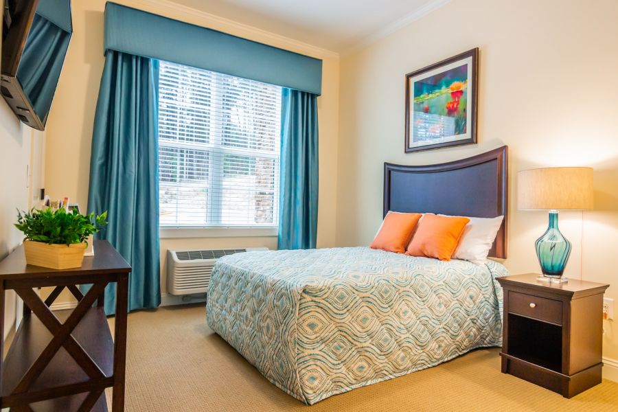 apartment bedroom with full sized bed, carpeting, and large windows