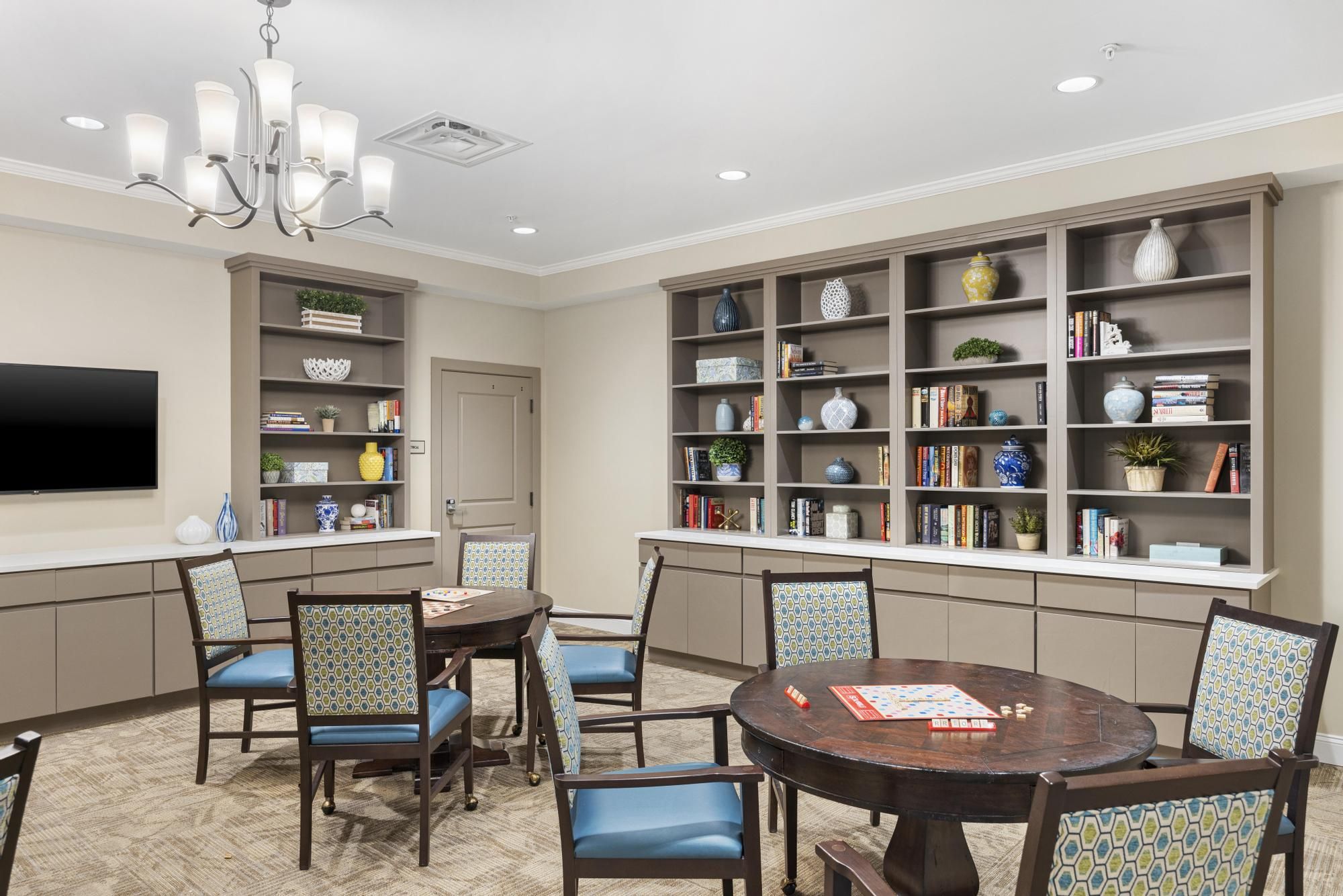 Brickmont at Woodstock resident dining room amenity with tables and chairs, a stone fireplace, and flat screen tv