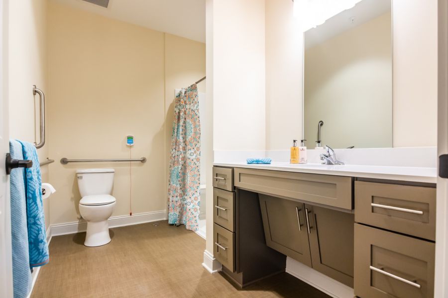 apartment bathroom with walk-in shower, accessible sink, and ample storage