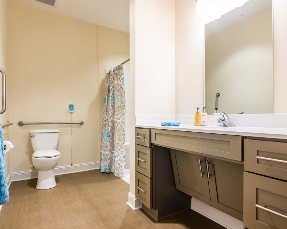 apartment bathroom with walk-in shower, accessible sink, and ample storage