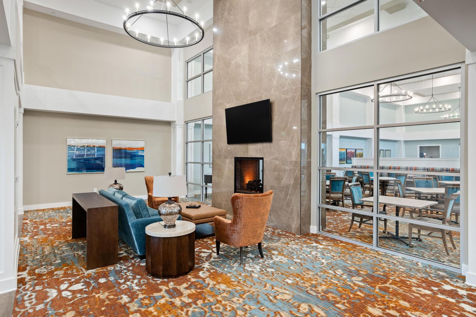 The Claiborne at Brickyard Crossing senior community lounge area with fireplace and tv