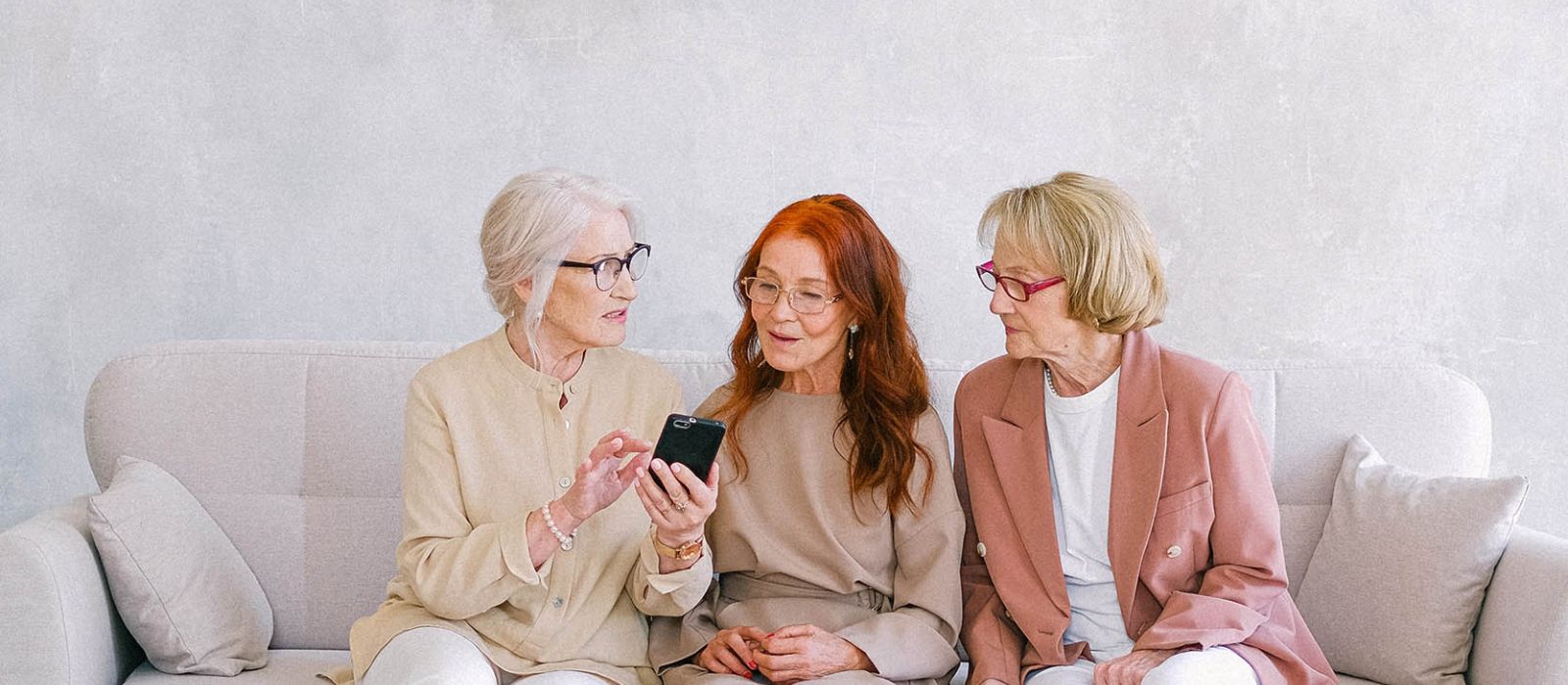 Group of women sitting on a couch having tea and cake