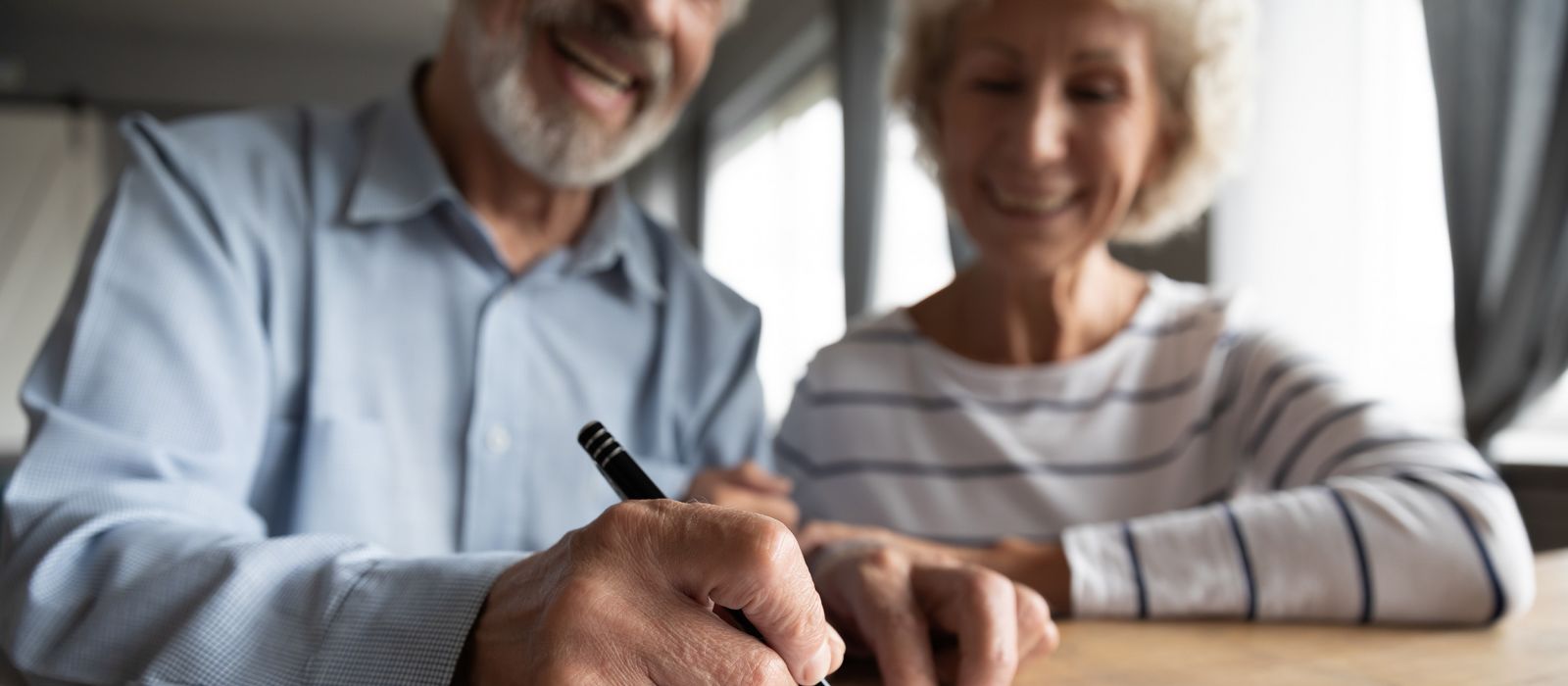 Close up focus on wrinkled male hand signing paper document. 