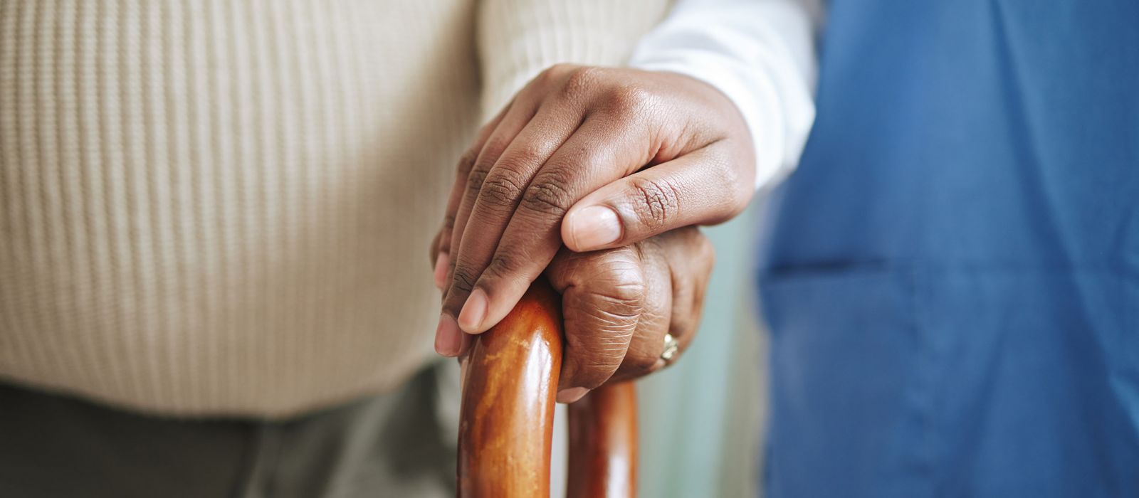 Cane, senior patient and nurse holding hands for support.