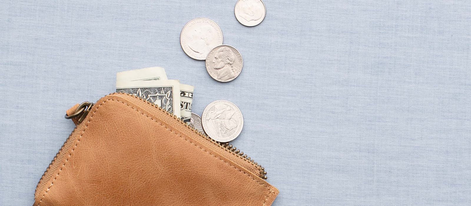 Tan leather wallet with dollar bills and coins spilling out.