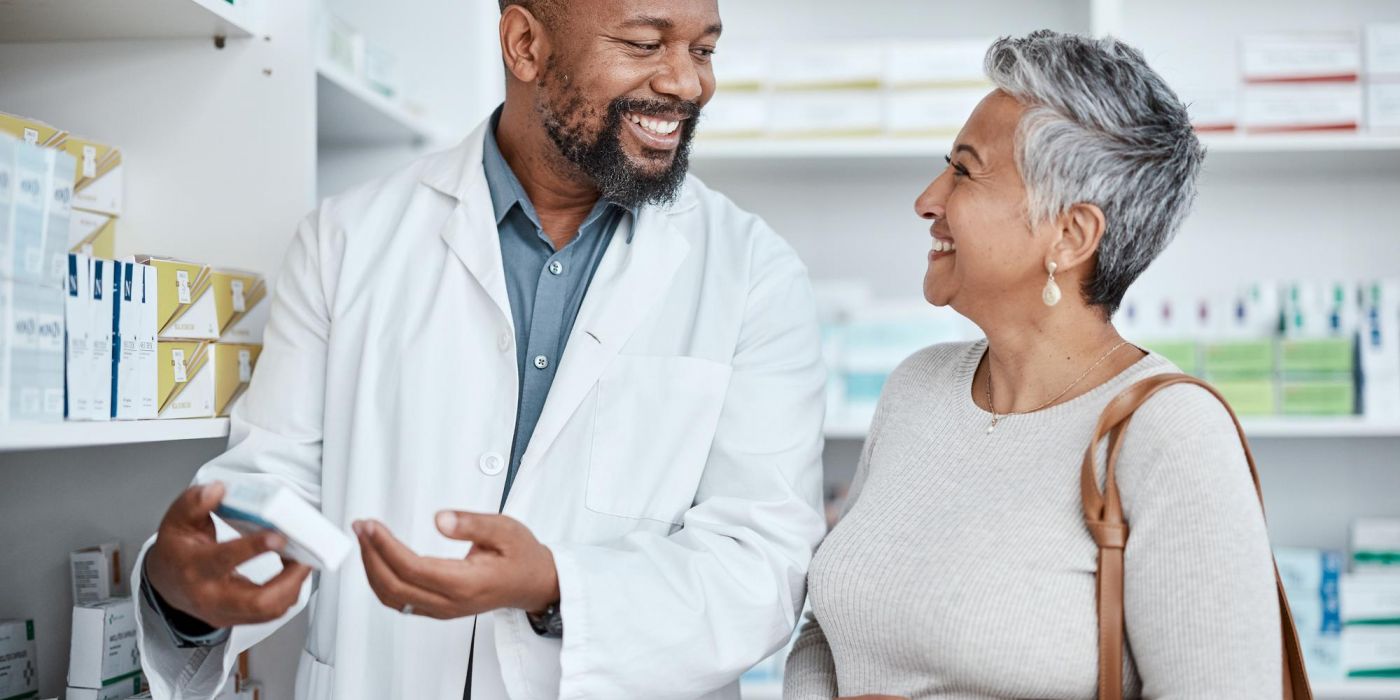 Smiling pharmacist assists a woman with medication in a pharmacy.