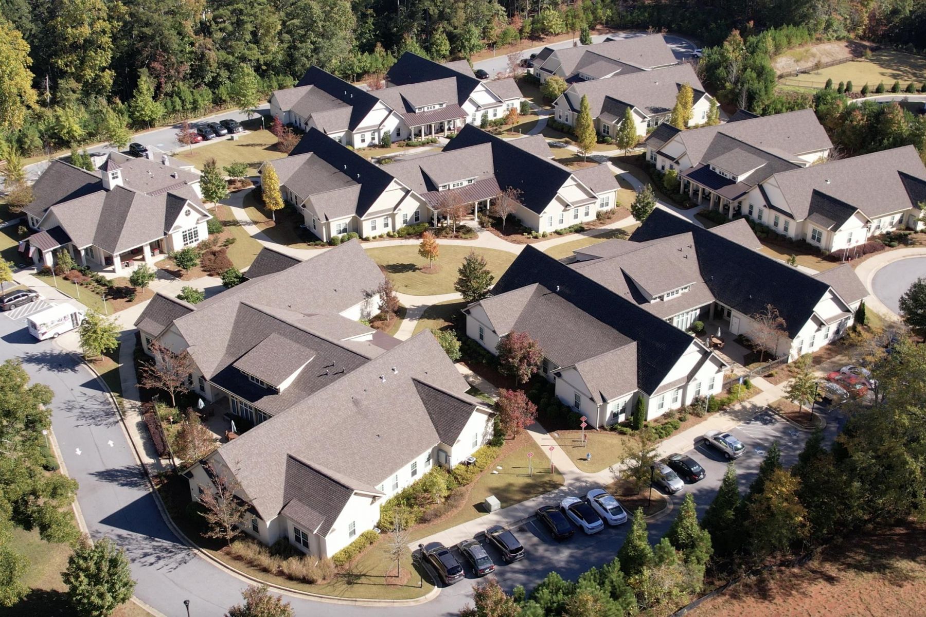 Camellia Place Aerial view of a residential neighborhood with multiple houses and parked cars surrounded by trees.