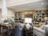Camellia Place Camellia Place A cozy living room with sofas, armchairs, lamps, plants, and built-in shelves filled with books and decor.