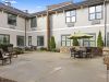 The Claiborne at Acworth Brickmont at Acworth senior living community outdoor courtyard patio with water fountain, gardens, tables, chairs, and umbrellas