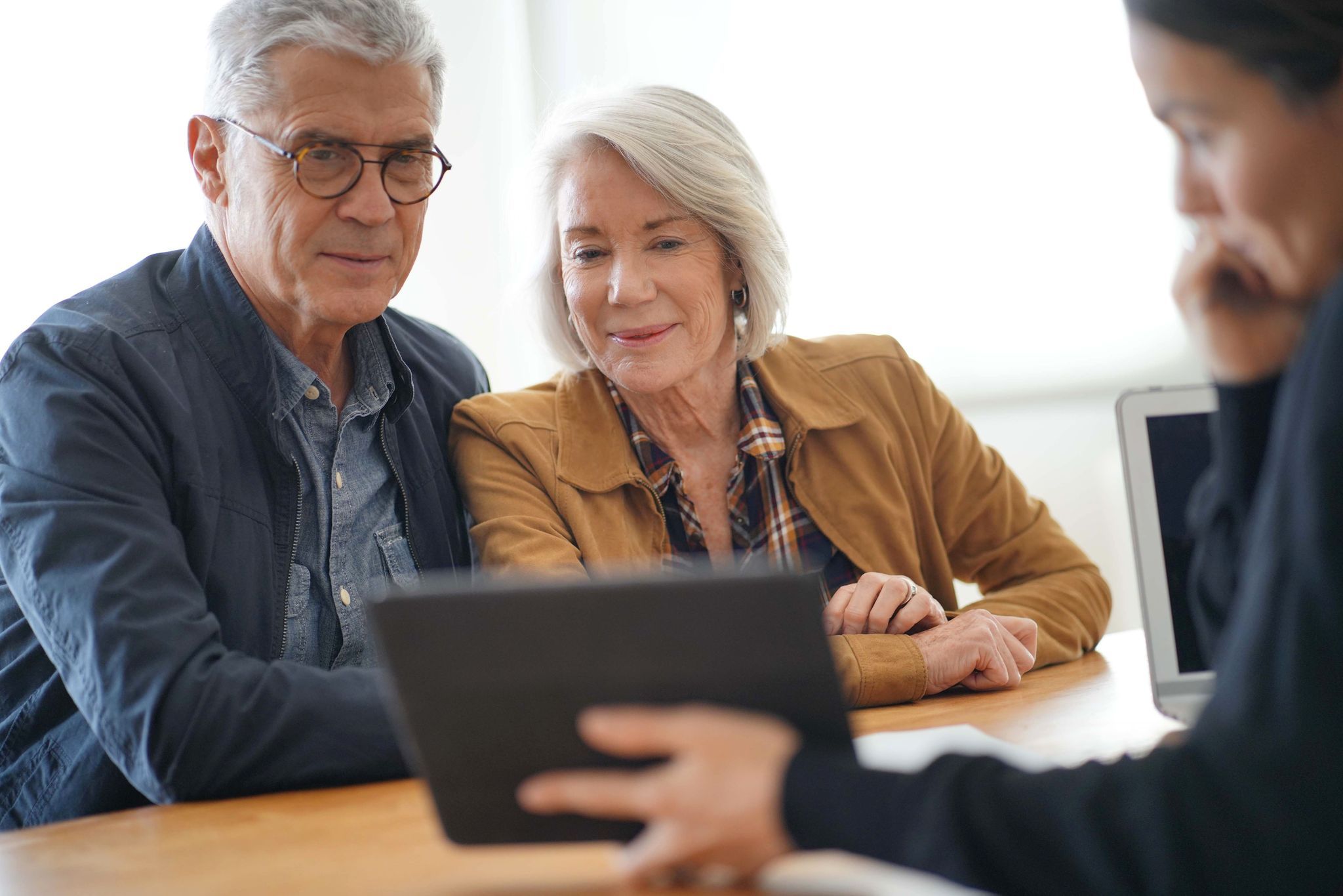 Modern senior couple looking at a tablet with an advisor.