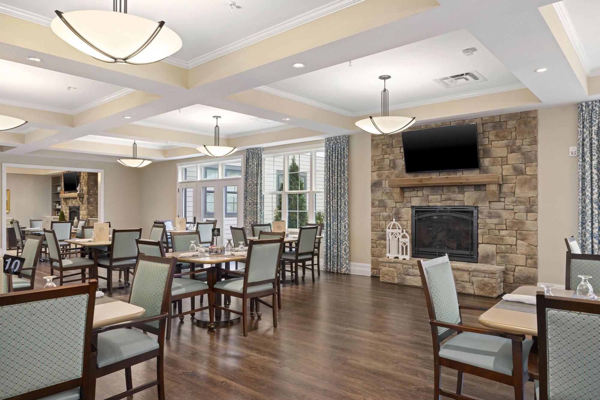 The Claiborne at Acworth resident dining room amenity with tables and chairs, a stone fireplace, and grand piano