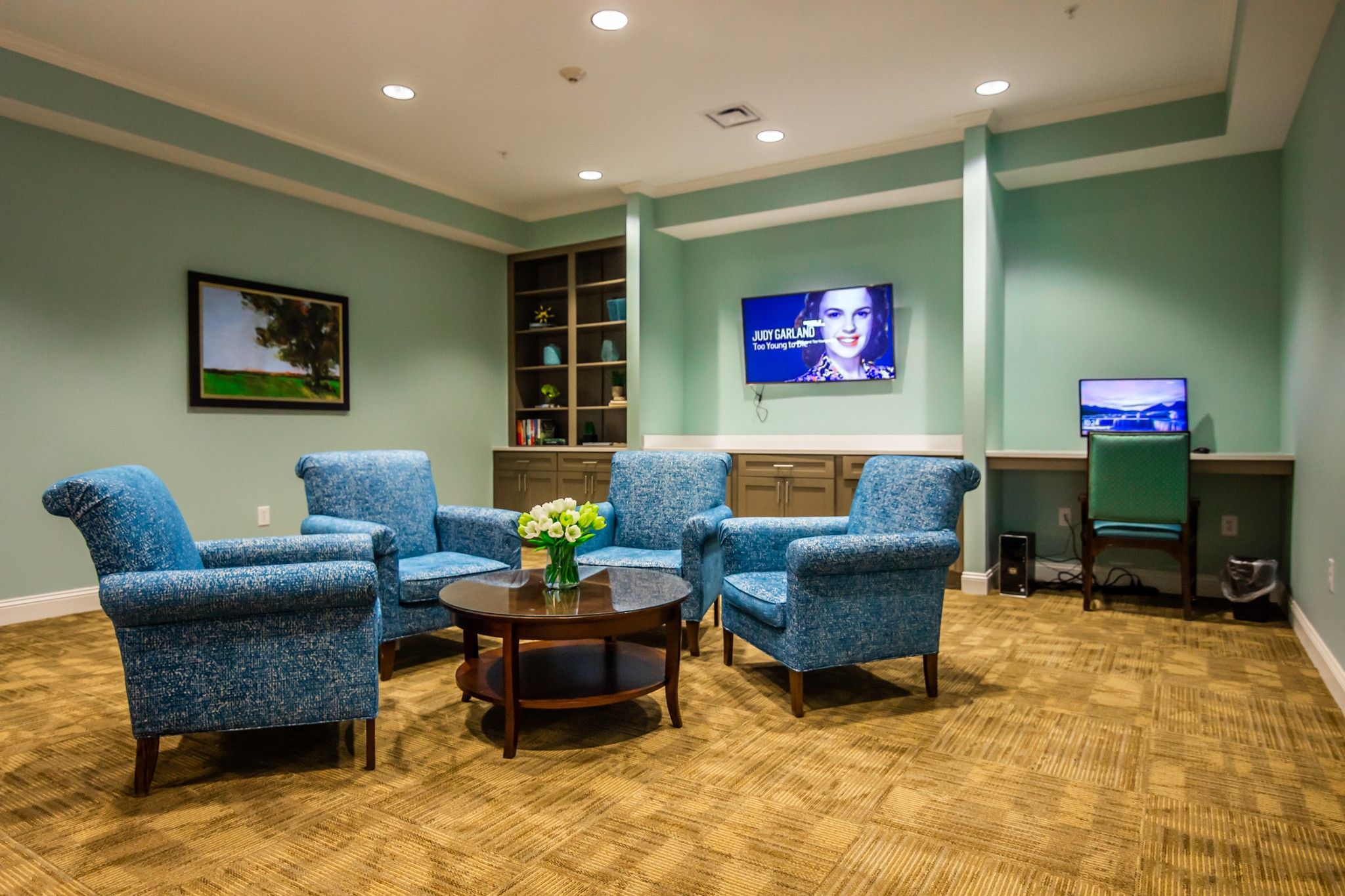 The Claiborne at Acworth common sitting area with lounge chairs, tvs, bookshelves, and a computer station