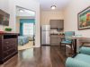 The Claiborne at Johns Creek senior living community apartment kitchenette, furnished living space, and large bedroom