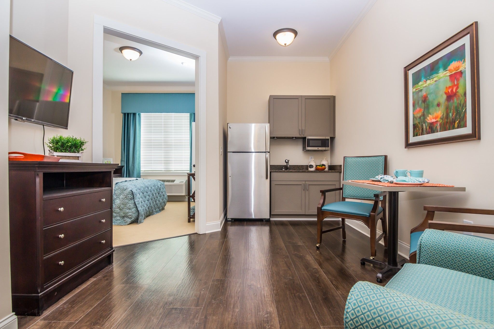 The Claiborne at Johns Creek senior living community apartment kitchenette, furnished living space, and large bedroom