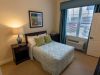 The Claiborne at Johns Creek senior living community apartment bedroom with full sized bed, carpeting, and large windows