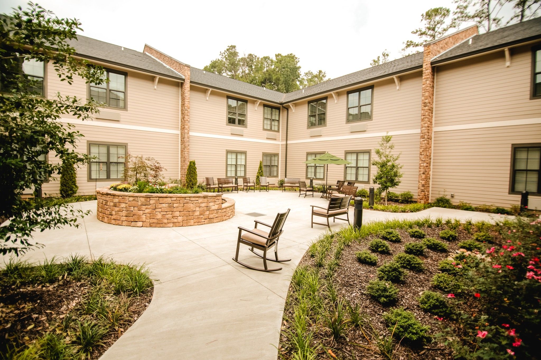 The Claiborne at Roswell outdoor patio courtyard with gardens, tables, chairs, and umbrellas