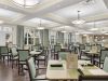The Claiborne at Roswell resident dining room amenity with tables and chairs, a stone fireplace, and grand piano