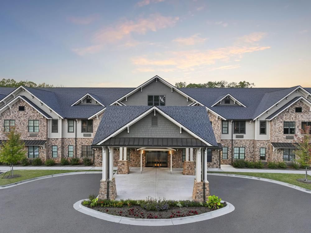 The Claiborne at Roswell  assisted living community exterior and parking lot surrounded by forest