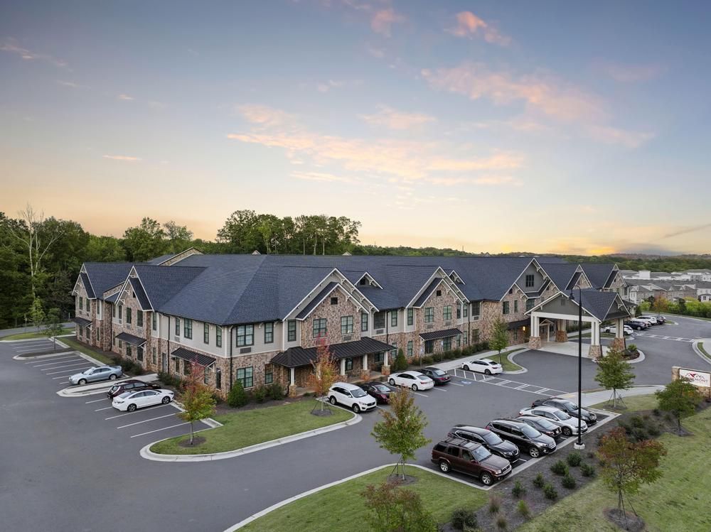 The Claiborne at Roswell   assisted living community exterior and parking lot surrounded by forest